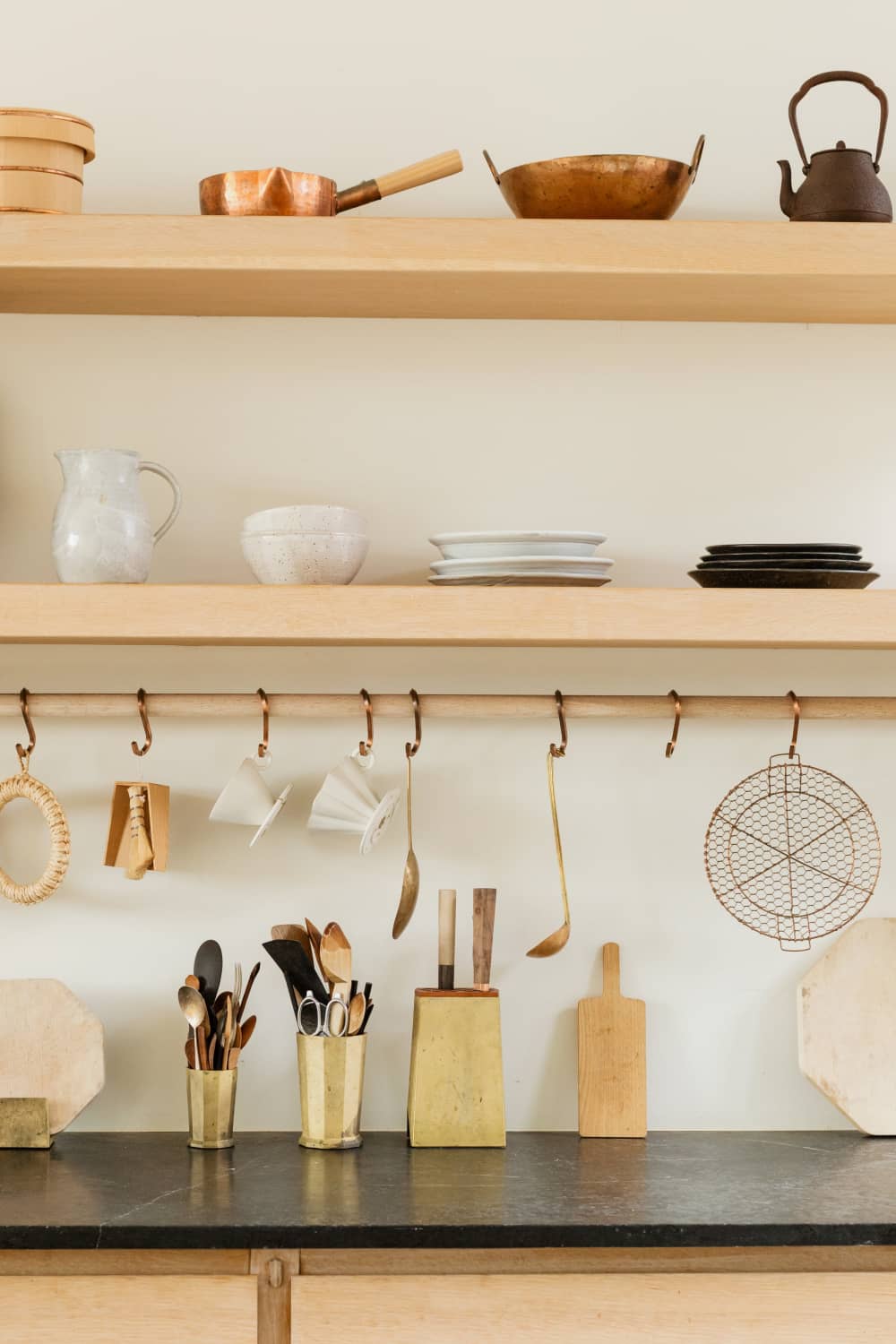 Wooden kitchen shelves with hanging utensils and organized cooking tools